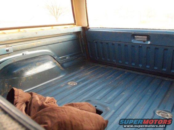 Interior cargo area of a 1985 Ford Bronco, showing blue metal floor and side panels