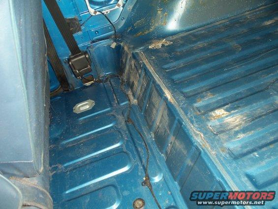 blue interior floor of a vehicle with seatbelts and some rust spots
