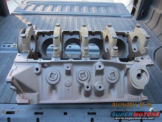 Engine block sitting in the bed of a pickup truck. It has the main bearing caps bolted on