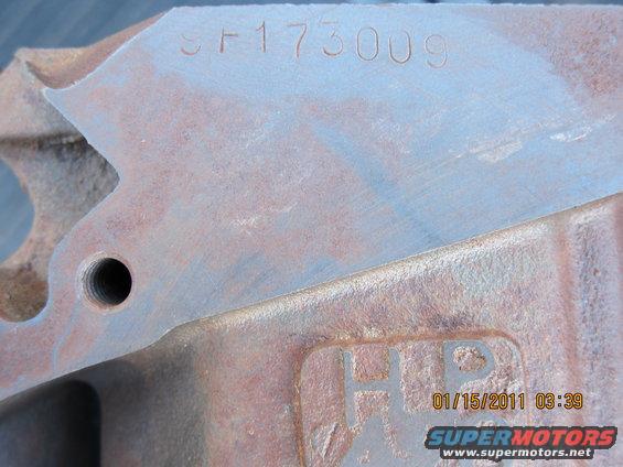 Close-up of a rusty metal engine part with the serial number SF173009 stamped on it