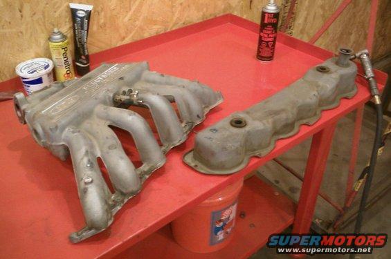 Ford intake manifold and valve cover on a red cart with cans of lubricant and cleaner