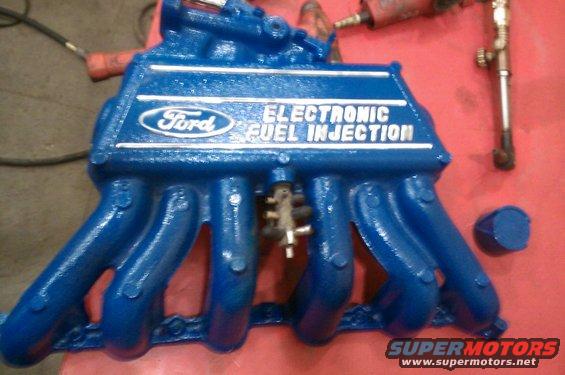 Blue Ford Electronic Fuel Injection manifold with white lettering on a red surface