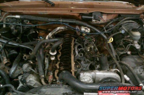 Engine bay with visible hoses and wiring. Supermotors.net logo at bottom right
