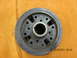 1969 Ford Mustang - A close-up view of a car part, a crankshaft pulley, is shown against a textured orange background.