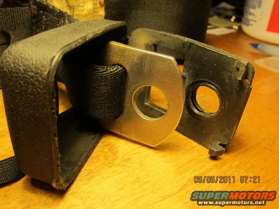 Black seatbelt buckle and strap on a wooden surface