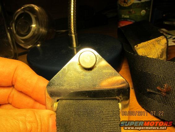 Close-up of a seatbelt buckle and strap with visible text on the strap