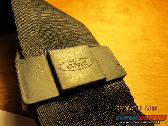 Close-up of a black seatbelt with a Ford logo on the buckle