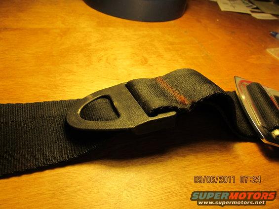 Black seat belt buckle with metal clasp on a wooden surface