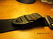 1969 Ford Mustang - Close-up of a black seat belt buckle and strap with visible stitching and a metal clasp.