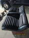 1969 Ford Mustang - Black vinyl bucket seats with ribbed pattern are shown next to a dark-colored truck.