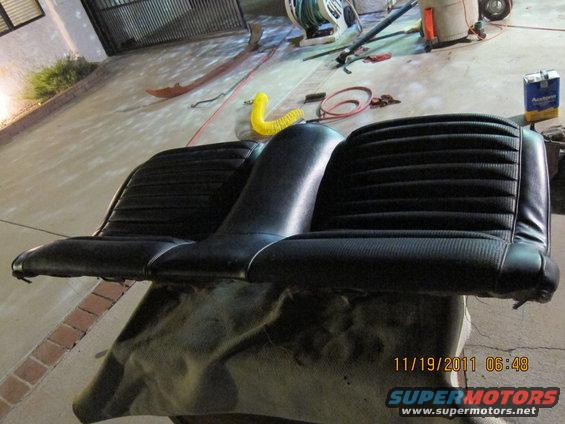 Black vinyl car seat with ribbed upholstery, resting on a tarp