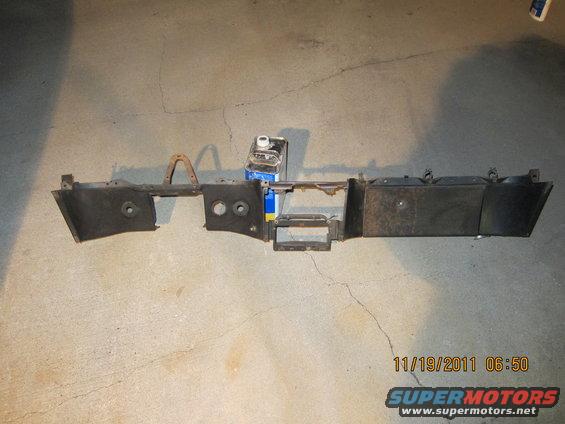Car dashboard section with two circular cutouts and a rectangular opening, resting on a concrete floor