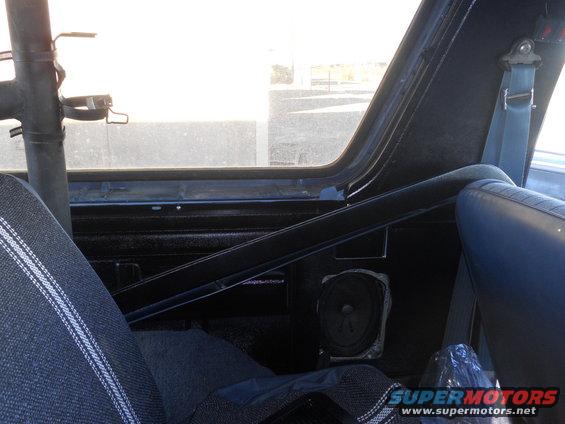 Interior shot of a vehicle showing a roll cage, speaker, and blue seats. A watermark reads 'SUPERMOTORS.NET'