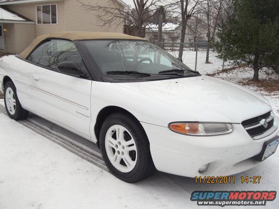 White convertible with tan top parked in snow. Chrysler logo visible on fender