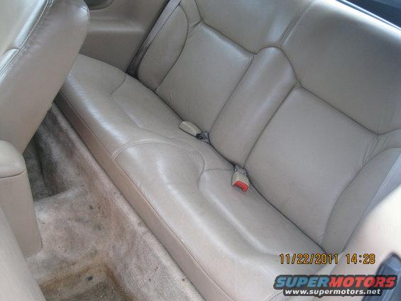 Tan leather rear seats with seatbelts and carpeted floor