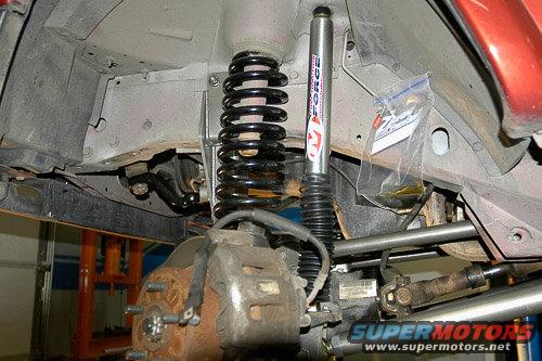 Vehicle suspension components including a shock absorber, coil spring, brake caliper, and driveshaft. A bag of hardware is attached to the frame