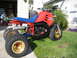 1985 Honda ATC 250 R - This 1985 Honda ATC 250 R features a red body, blue seat, and gold wheels, parked on a grassy lawn.