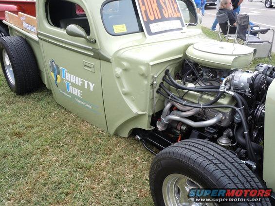 Custom pickup truck with "Thrifty Tire" logo on door and exposed V8 engine