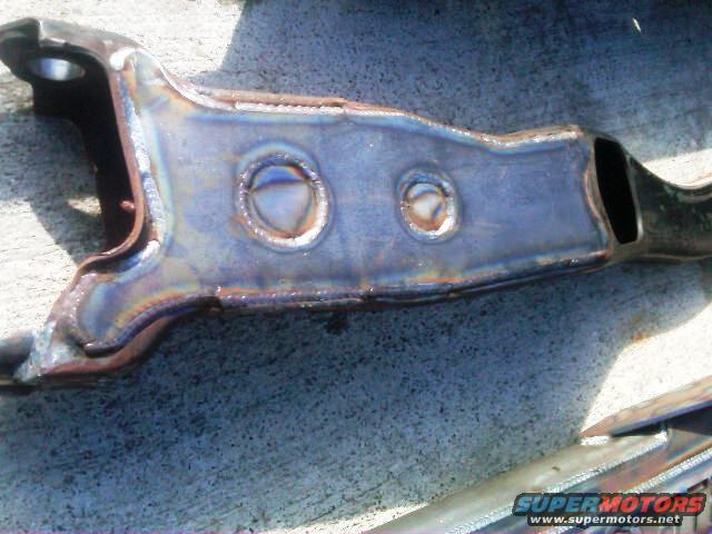 Modified suspension part with visible welds and circular cutouts