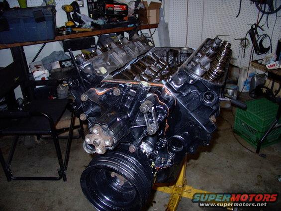 Engine on a yellow stand in a garage with tools on a shelf in the background