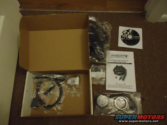 Innovate standalone gauge kit with manual, CD, and various components laid out on carpet