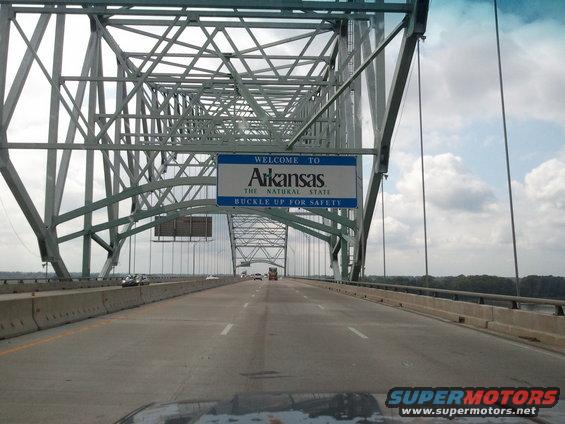 View from a vehicle crossing a bridge into Arkansas, with a welcome sign overhead