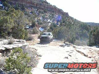 White SUV on a dirt road in a rocky, arid landscape