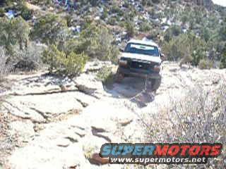 White SUV on rocky desert trail. Super Motors logo visible