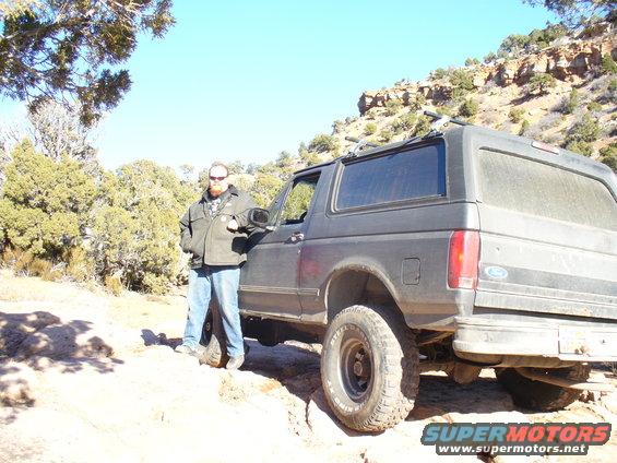 Man leaning on a dark 1992-1996 Ford Bronco in a rocky, outdoor setting