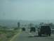 1986 Ford Bronco - Multiple SUVs are seen driving on a highway under a hazy sky.
