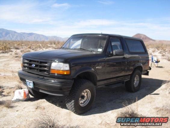 Black Ford Bronco parked in a desert with mountains in the background