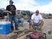 1986 Ford Bronco - Men grill meat at a desert campsite with trucks in the background.