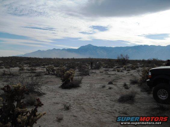 Black SUV parked in a desert landscape with mountains in the background