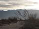1986 Ford Bronco - A desolate desert scene with mountains in the background and dry brush in the foreground, under a cloudy sky.