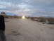 1986 Ford Bronco - A person stands on a dirt road in the desert, looking towards distant headlights as the sky darkens.