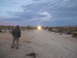1986 Ford Bronco - A person surveys a desert scene with headlights visible in the distance.