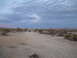 1986 Ford Bronco - A lone SUV navigates a dusty track through a barren desert environment.