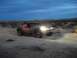 1986 Ford Bronco - A modified off-road truck races across a desert landscape as the sun sets.