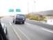 1986 Ford Bronco - Black Ford Bronco driving on a highway with directional signs in the background.