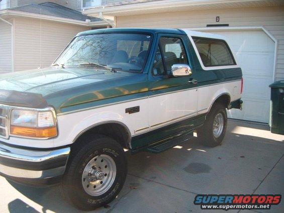 Green and white Ford Bronco with running boards parked in a driveway