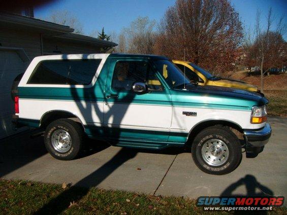 1996 Ford Bronco parked next to a yellow vehicle