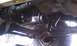 1979 Ford Bronco - Close-up view of the exhaust system and drivetrain components underneath a vehicle.