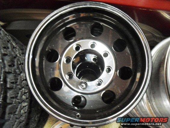 Chrome wheel with ten lug holes and a polished rim, next to a tire