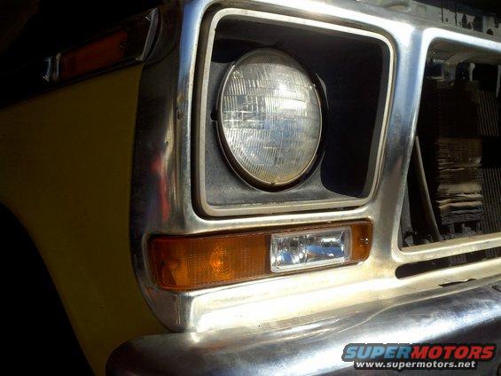 Close-up of a yellow Ford truck's front end, showing the headlight and grille area