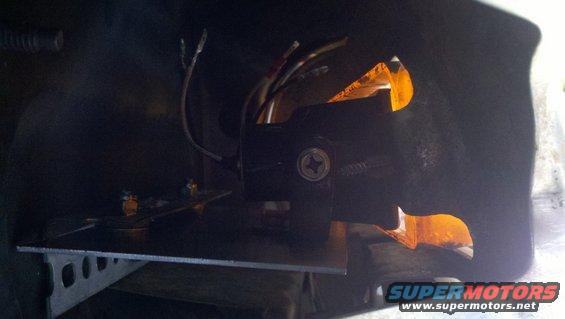 Black fog light assembly with orange reflector and exposed wiring, mounted on a metal bracket
