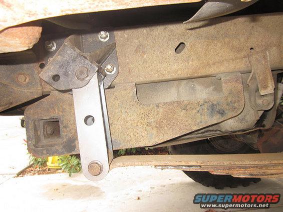 Close-up of rusty vehicle frame with aftermarket suspension part attached