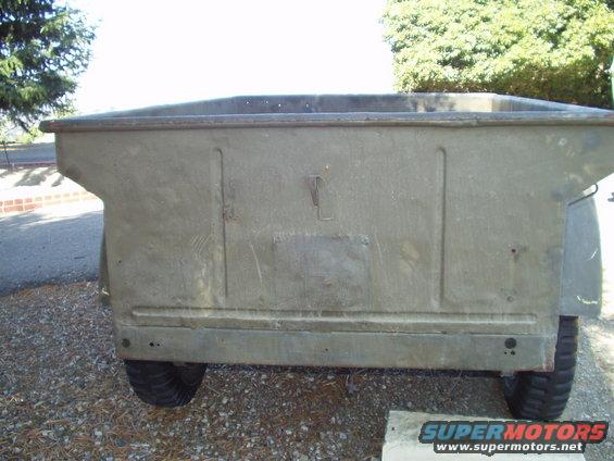 Rear view of a drab green military trailer with two wheels visible