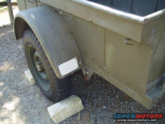 Olive drab trailer fender and wheel, supported by concrete blocks