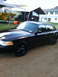 2001 Ford Crown Victoria - A black 2001 Ford Crown Victoria is parked outside a house with a boat and another vehicle under a canopy.