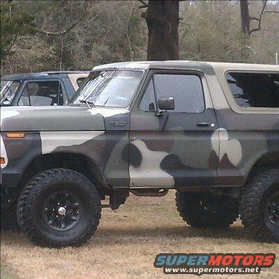 Camouflaged Ford Bronco, side view, with another vehicle behind it